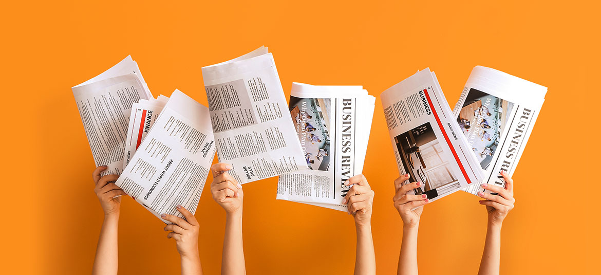hochgehaltene Zeitungen auf orangem Hintergrund
