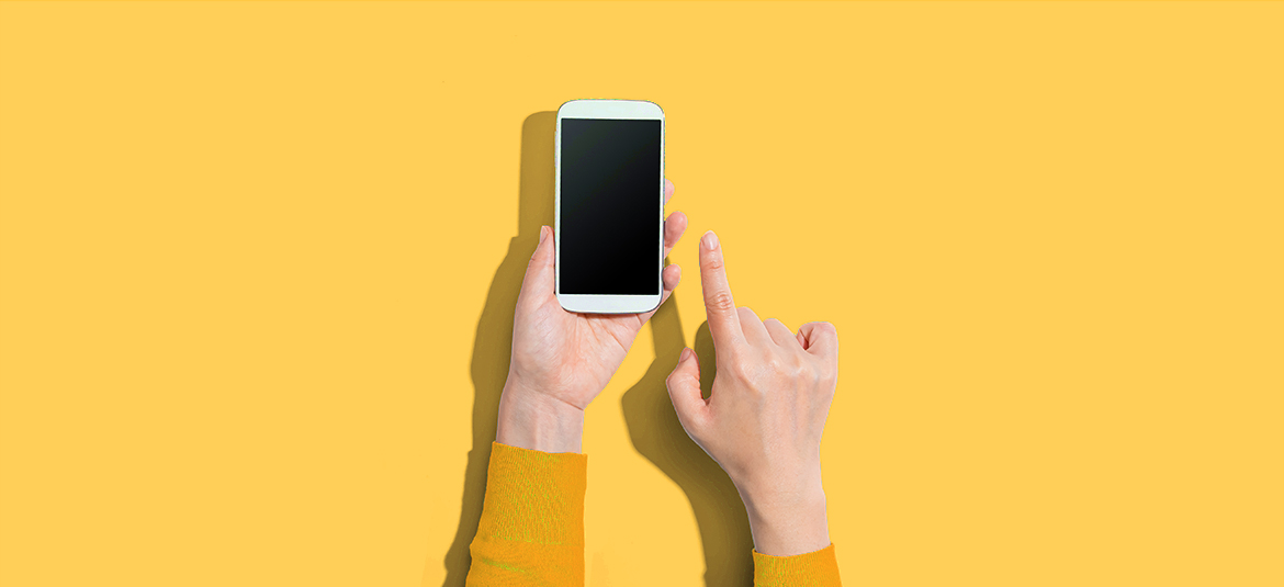 Hände mit Smartphone auf gelbem Hintergrund